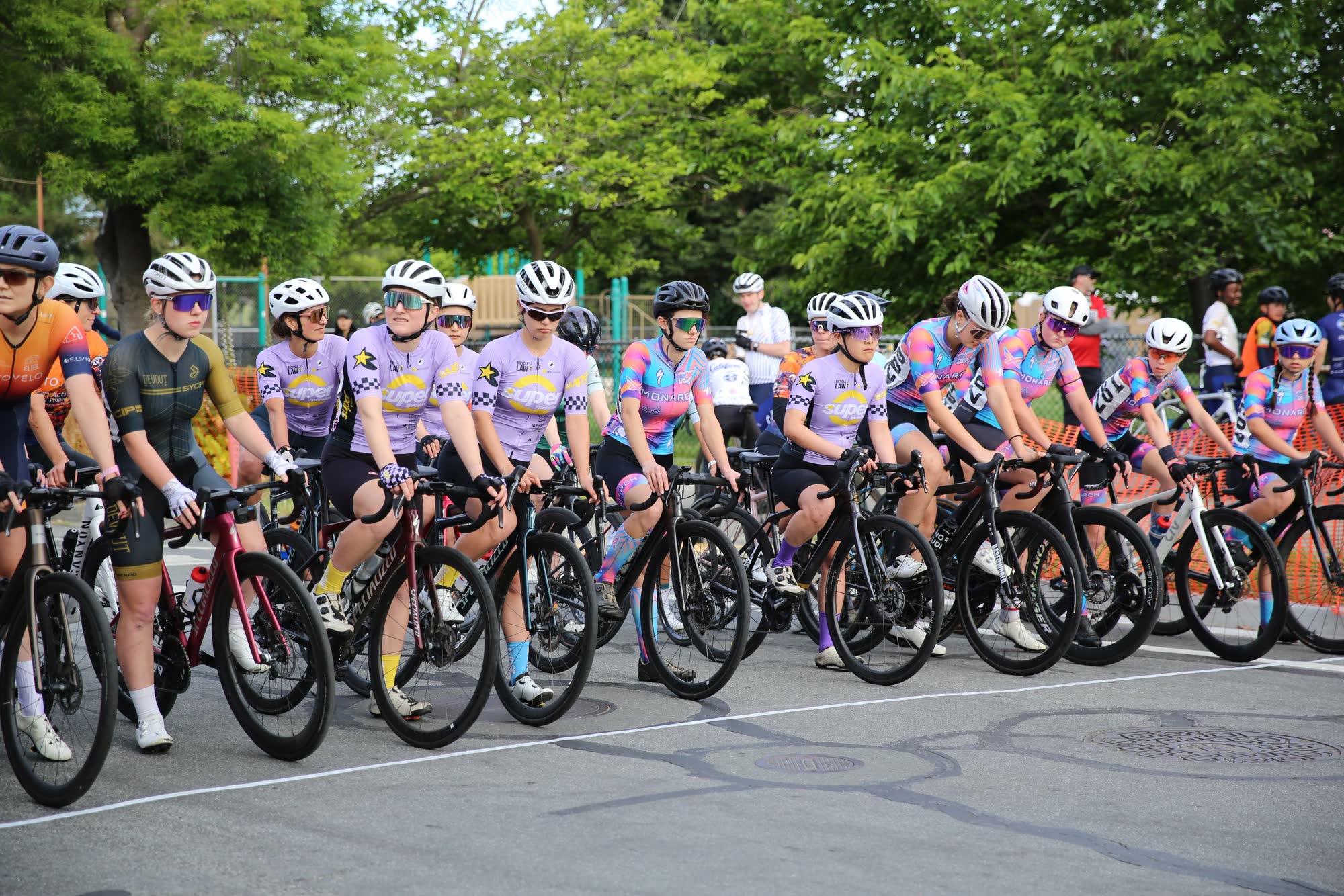 A women's field in lavender and pink kits lined up at the start of the Berkeley Streets Criterium