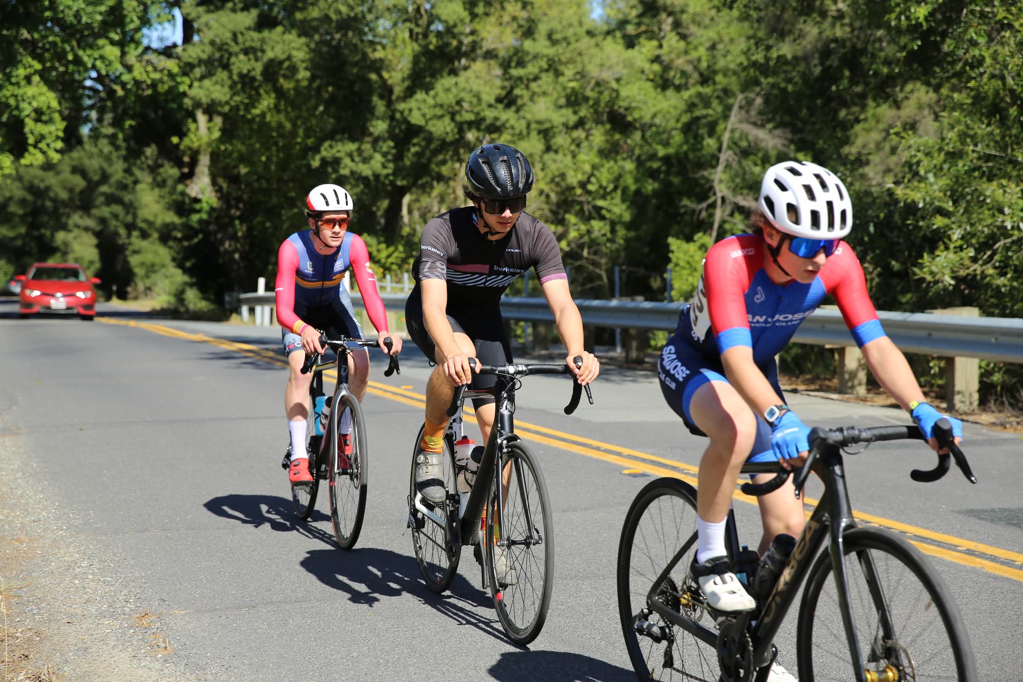 Three junior riders riding together on a tree-lined road