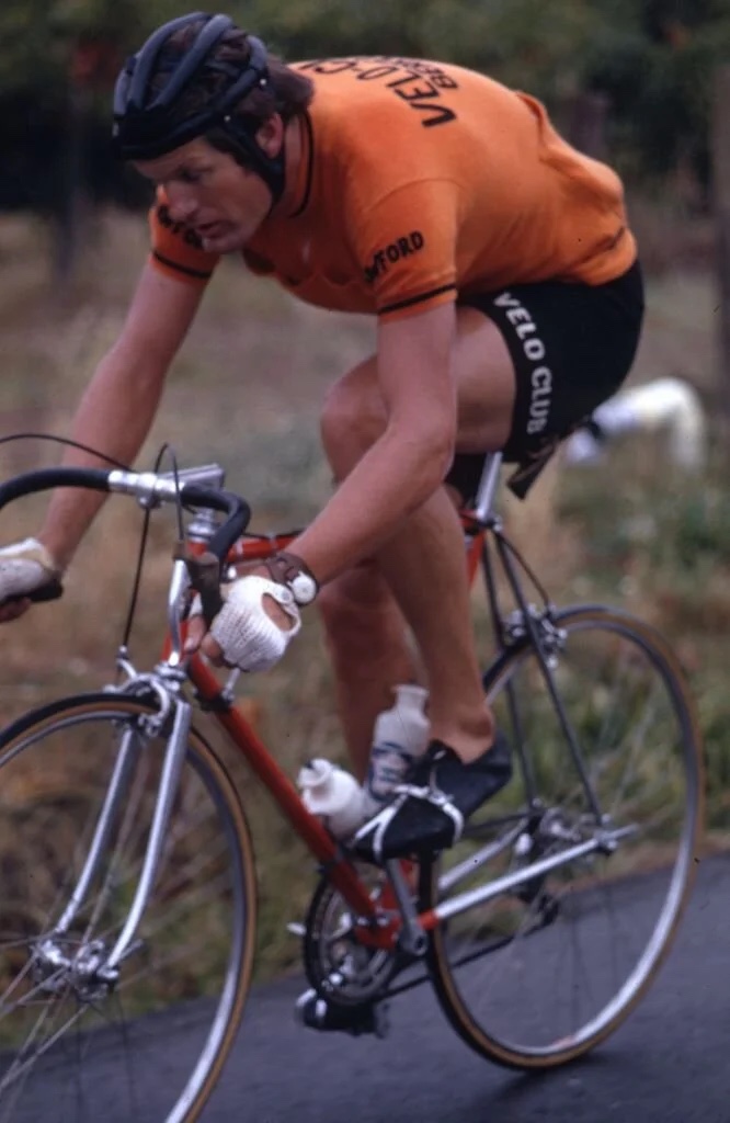 A rider in an orange Velo Club Berkeley jersey on a country road