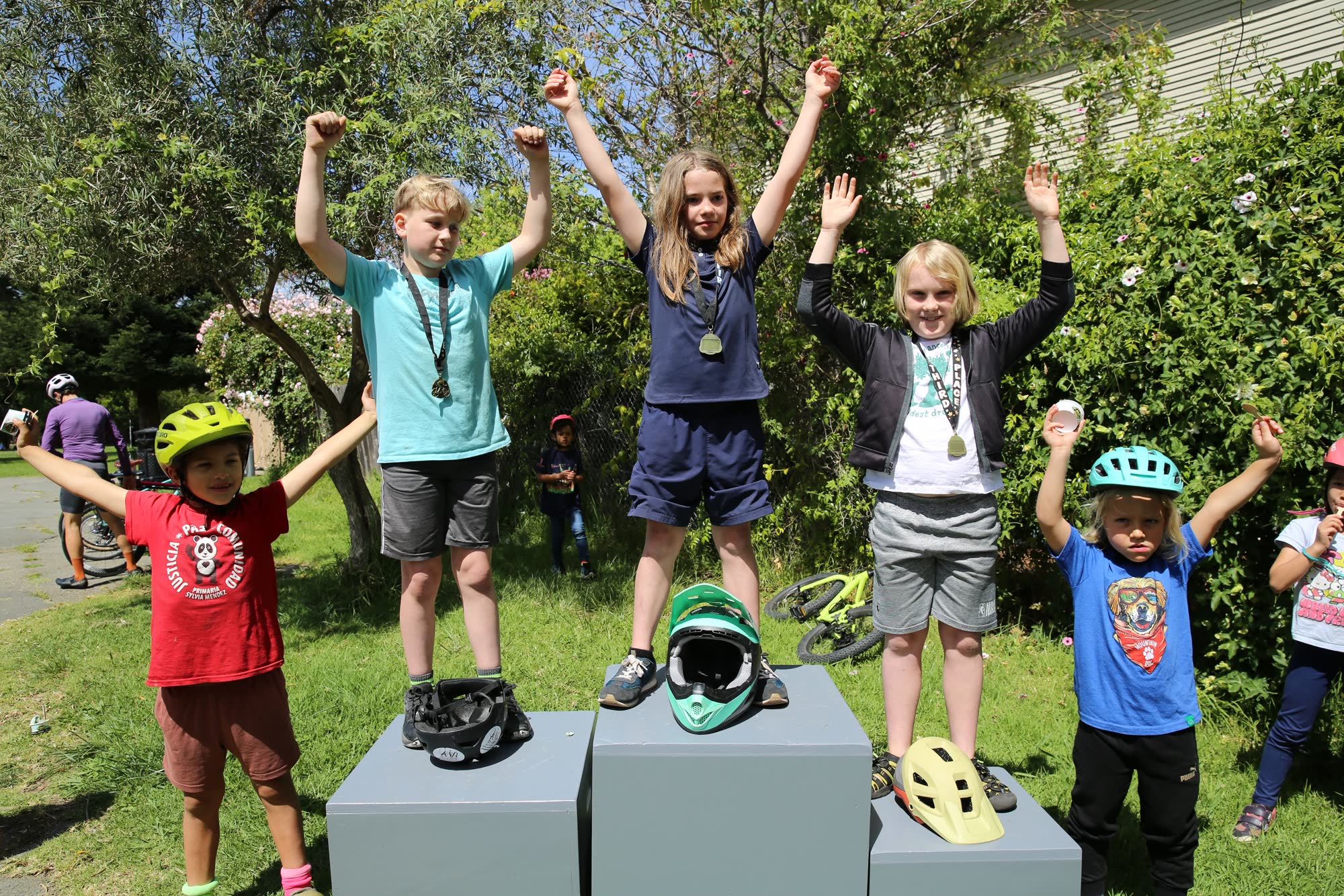 Young riders cheering on a podium with medals after the kids race