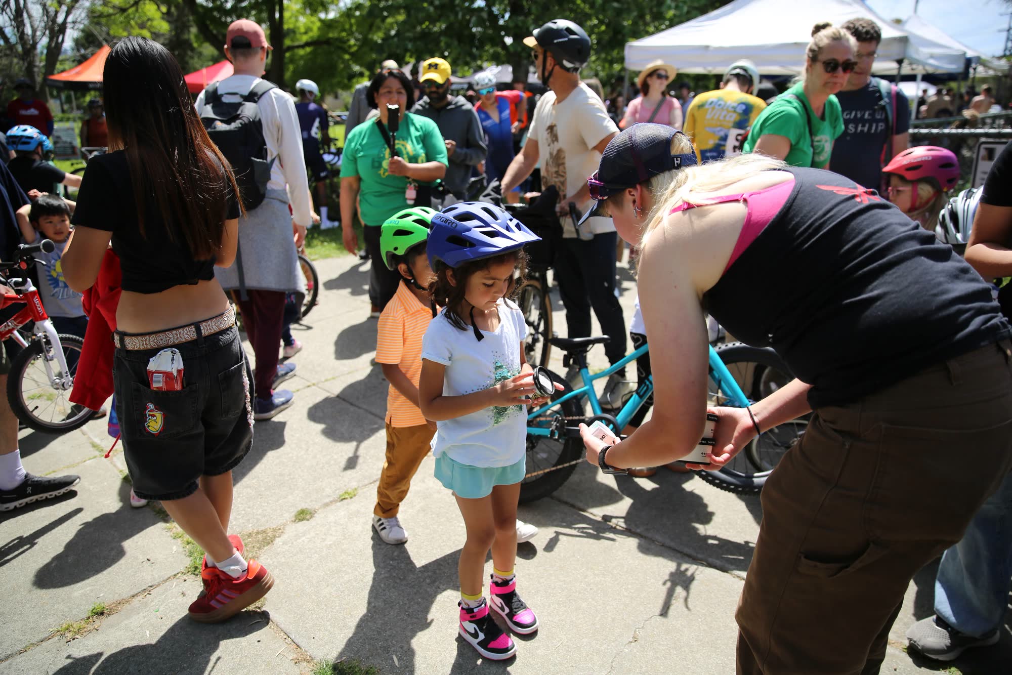 An adult helping a young rider with her bike