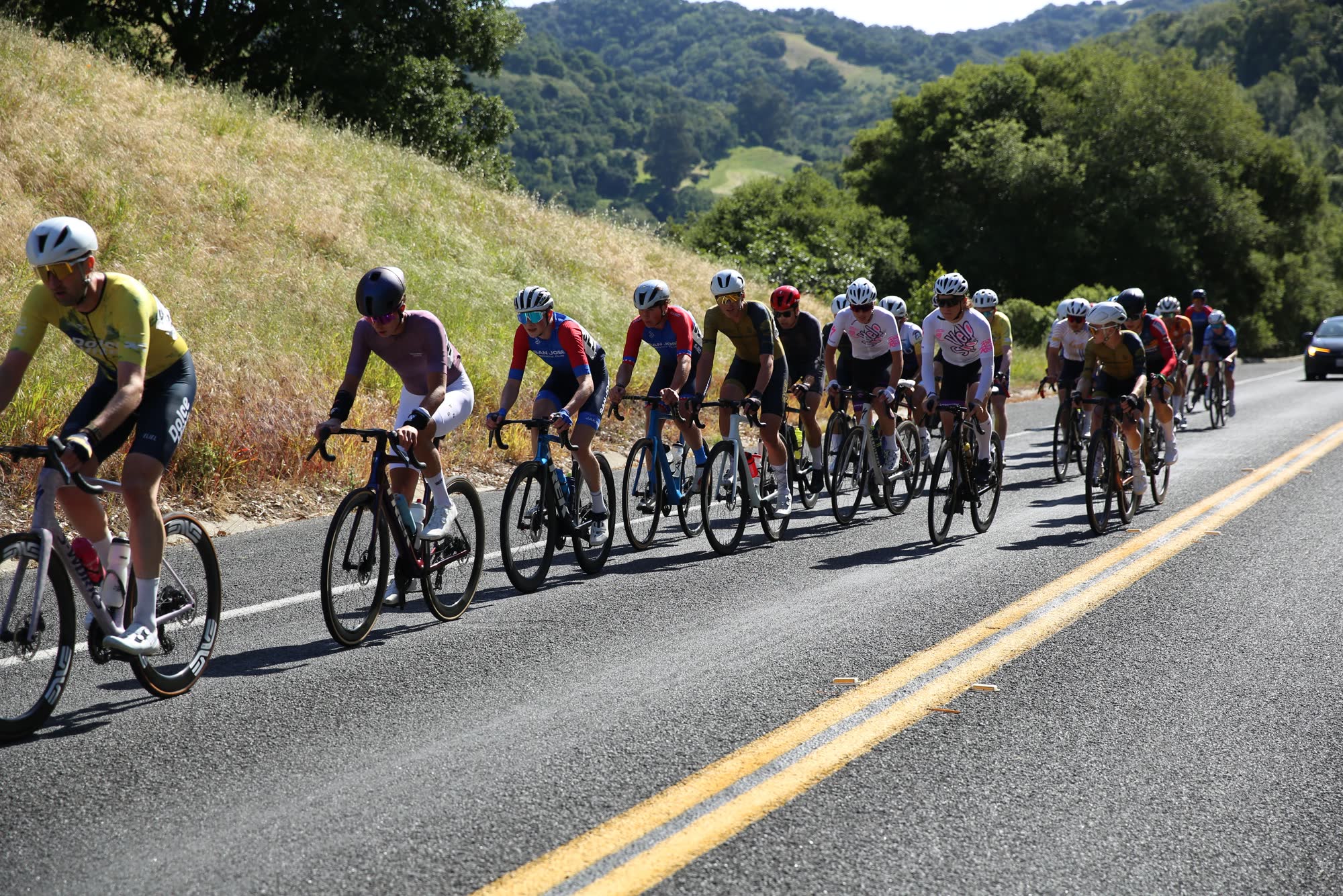 The peloton climbing beside a grassy hillside at the Berkeley Hills Road Race