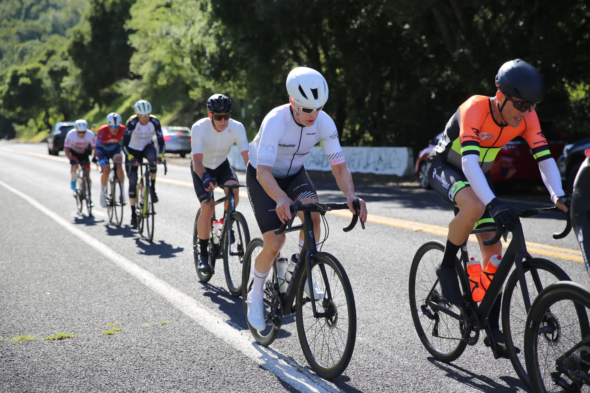 Riders in white and orange kits at the front of a group at the Berkeley Hills Road Race