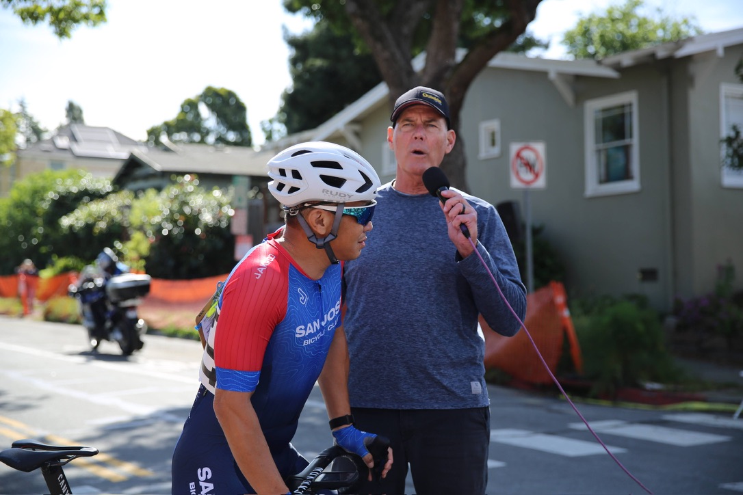 A race announcer with a microphone talking beside a rider at the Berkeley Streets Criterium